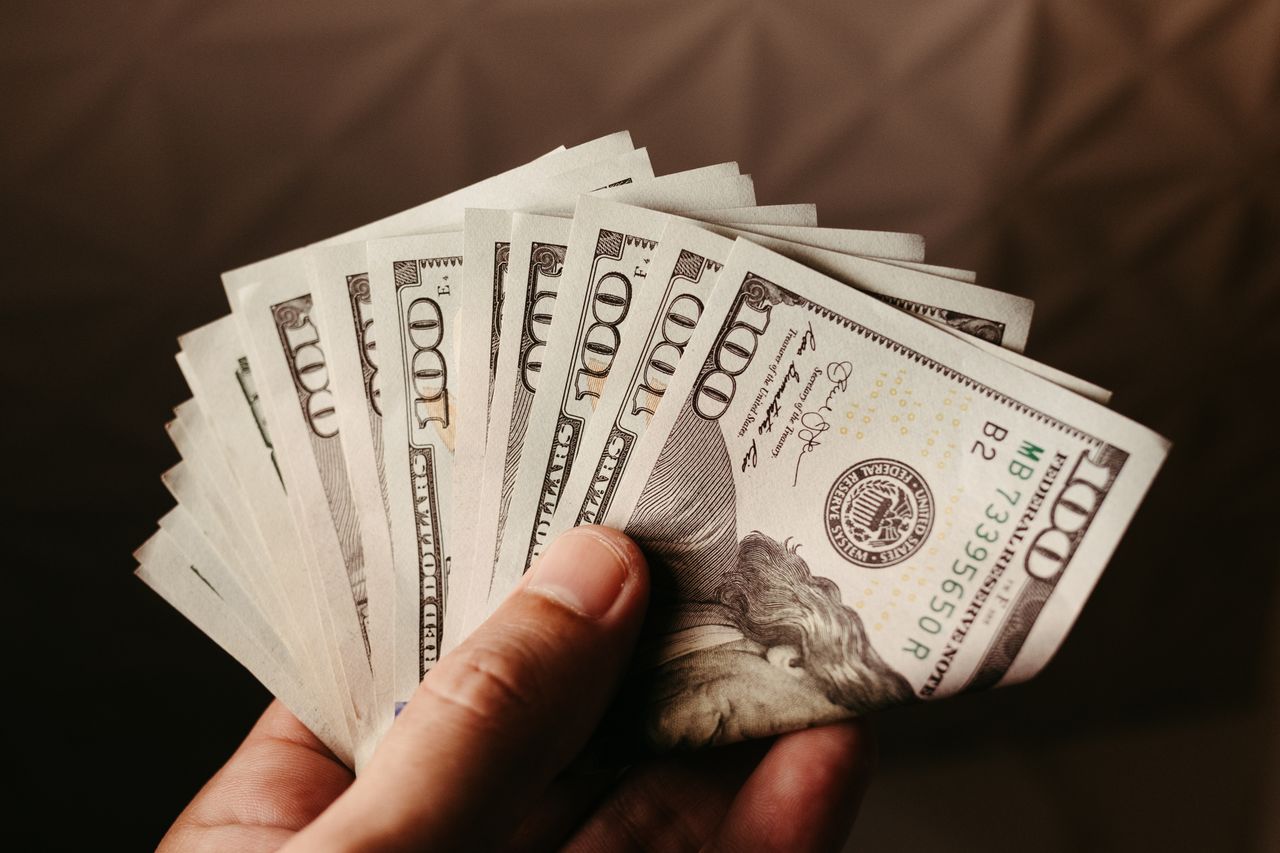 Fan of US hundred dollar bills held in hand, symbolizing wealth and finance.