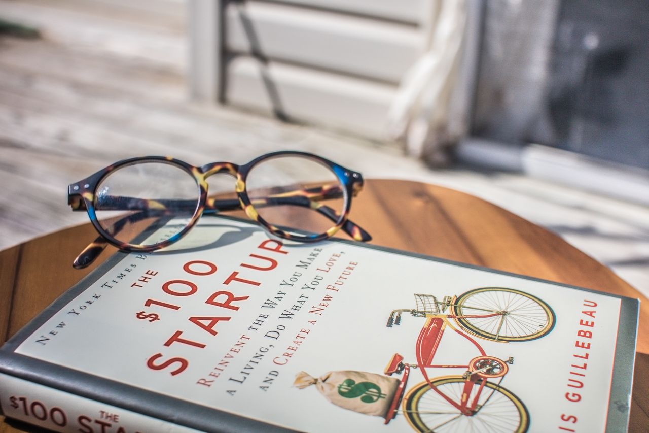 Close-up of a book and eyeglasses on a table, perfect for study or leisure reading.