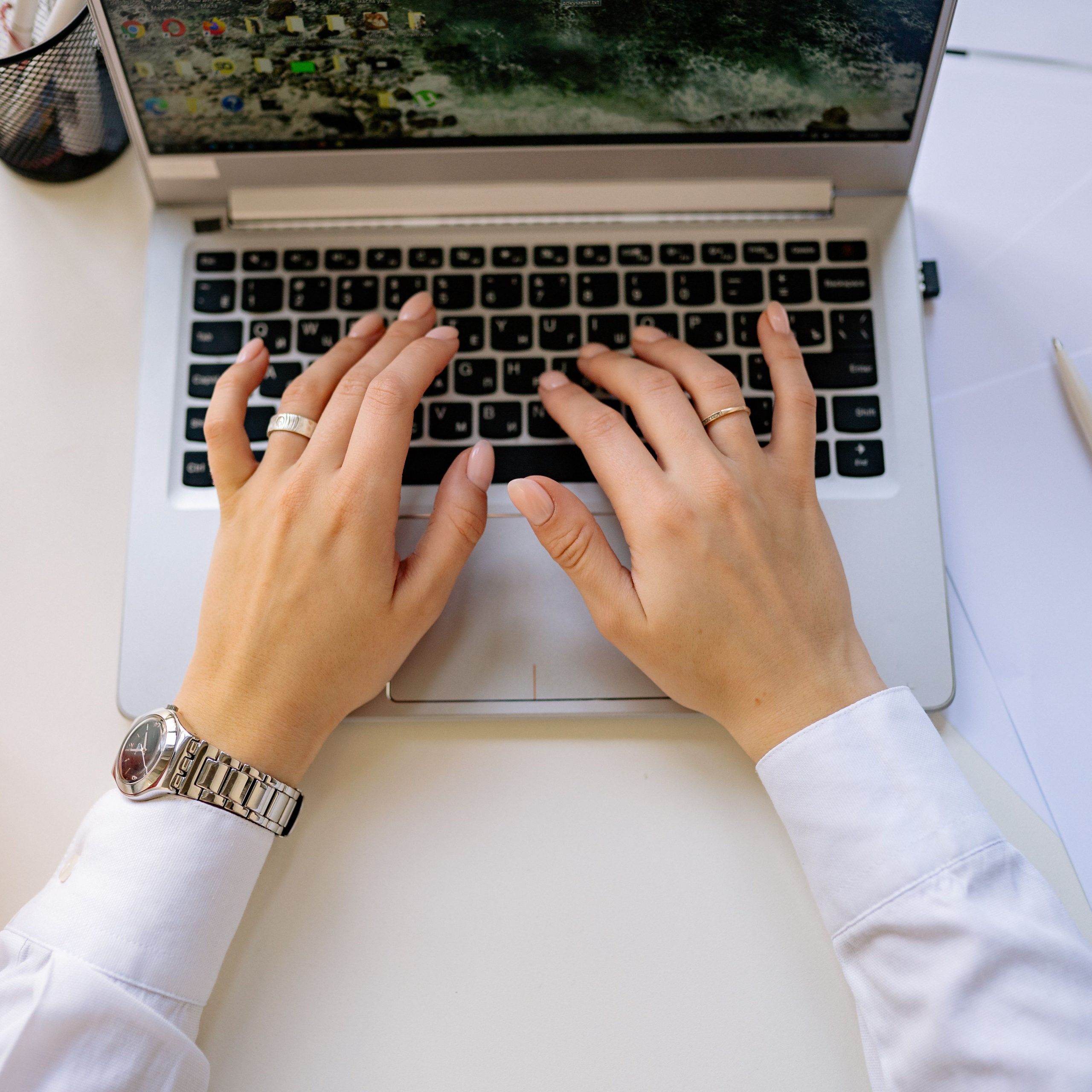 Hands typing on a sleek laptop keyboard in a bright, modern workspace. Ideal for business concepts.